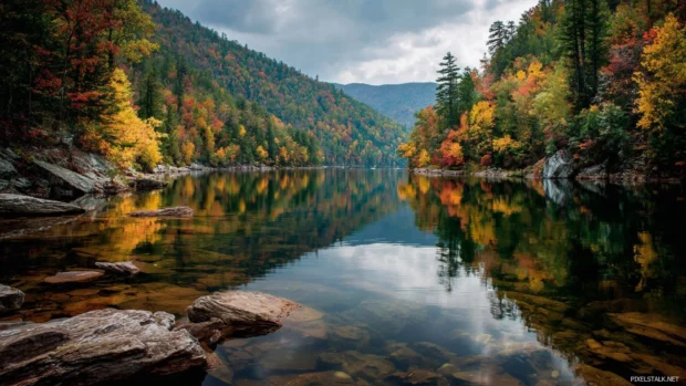 Fall landscape opening to a clear mountain lake, surrounded by forests shimmering with the full spectrum of autumn colors.