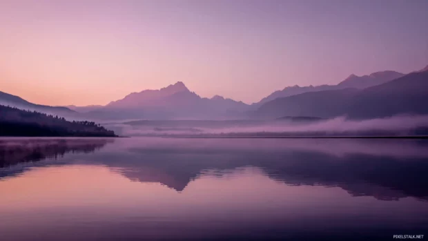 Lavender color haze rising over a calm lake with distant mountain silhouettes.