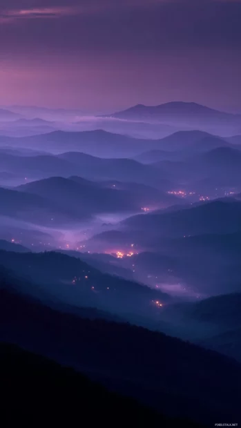 Lavender glow lighting up the edge of a mountain, surrounded by soft morning haze.