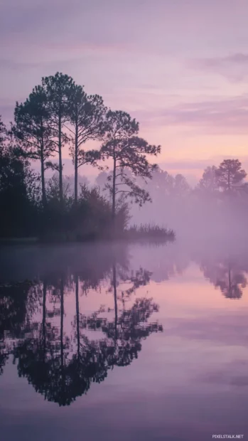 Lavender mist over a calm lake with silhouettes of trees and soft reflections.