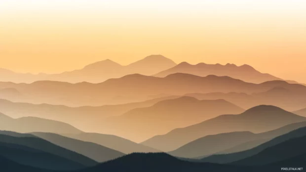 Mountain silhouette layered in Earth tone gradients with soft haze.