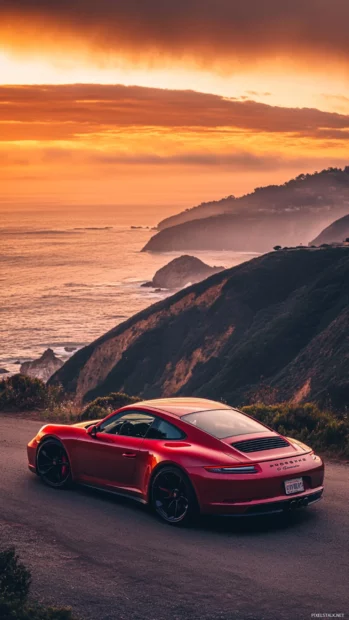 Porsche parked in front of a dramatic cliffside overlooking the ocean under golden light.