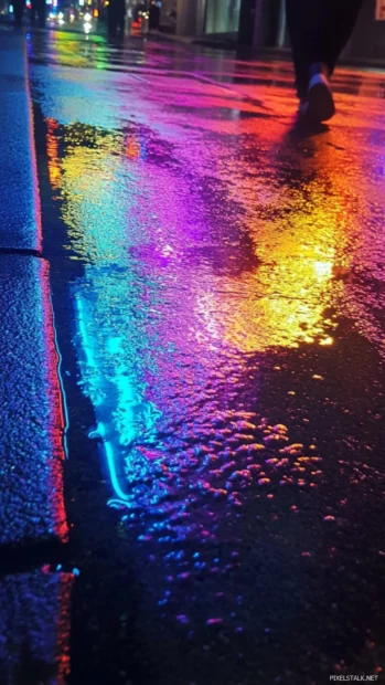 The neon lights of Japans Tokyo streets reflecting vividly in rain soaked pavements at night.