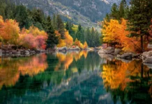 A calm lake reflects the vibrant tapestry of autumn trees surrounding it in this picture perfect landscape view.