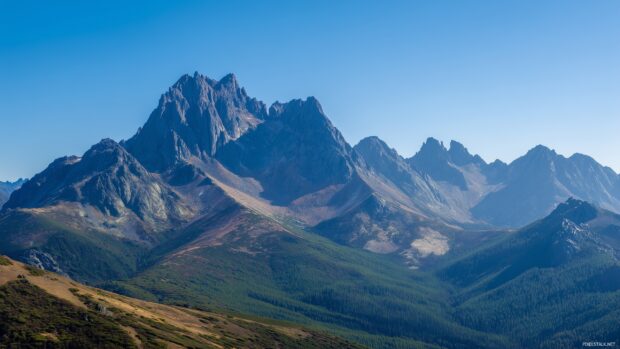 Amazing backgrounds free download, An expansive mountain range under a clear blue sky, showcasing jagged peaks and green valleys.