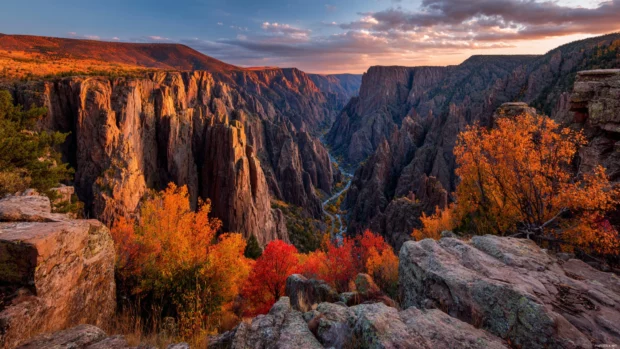 Autumn desktop wallpaper featuring panoramic Colorado canyon glowing in red and orange fall foliage.