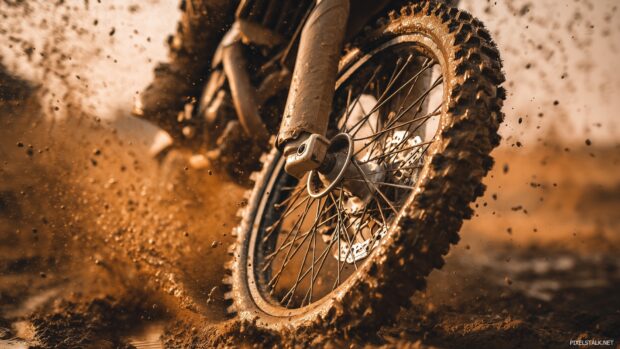 Download free HD dirt bike wallpapers with a close up perspective of a dirt bike tire splashing mud.