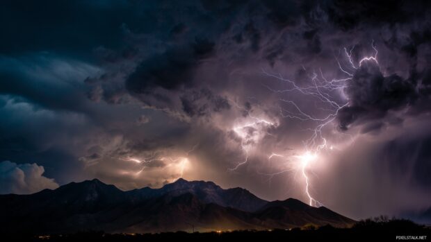 Electrifying storm desktop art, A mesmerizing view of lightning illuminating a mountain range during an intense thunderstorm.