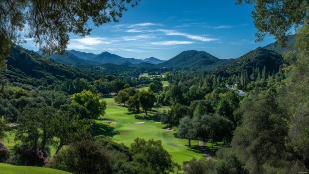 Golf wallpapers HD, A panoramic landscape of a lush golf course surrounded by vibrant trees and a clear blue sky.