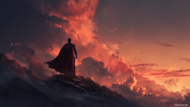 HD Superman wallpaper, An epic scene showcasing Superman standing strong on a mountaintop, with a dramatic sunset in the background.