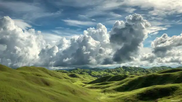 Live moving backgrounds for pc portraying dynamic clouds flowing over rolling green hills.