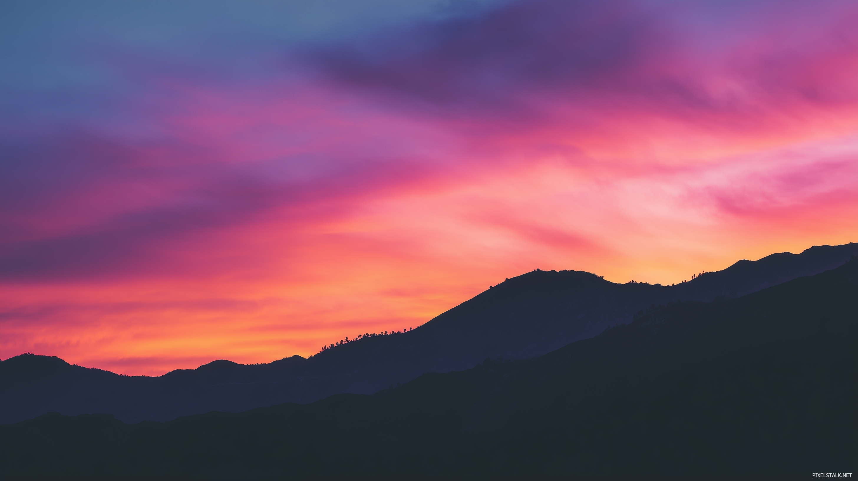 Vibrant laptop wallpapers featuring a sunset over a mountain ran.