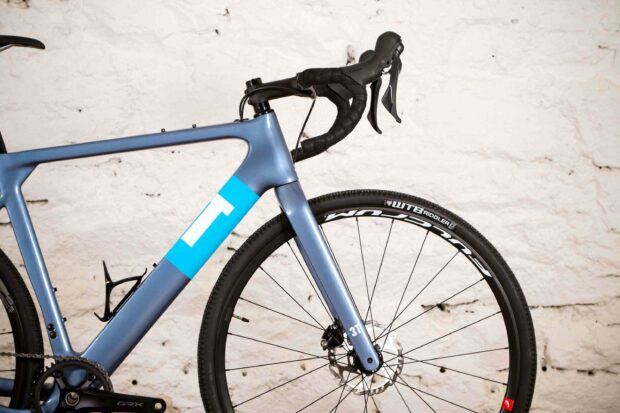 A 3T bike with a blue frame is shown in close up against a white brick wall, 2K Desktop Wallpaper
