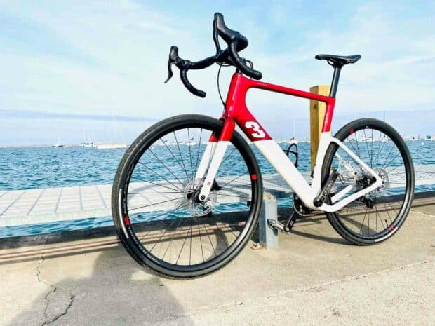 A 3T bike with a red and white frame is parked near the blue sea and sailboats, HD Desktop Wallpaper