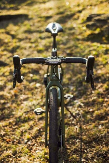 A 3T bike is positioned on a grassy ground under daylight, focusing on the handlebars and front wheel, 2K Phone Wallpaper