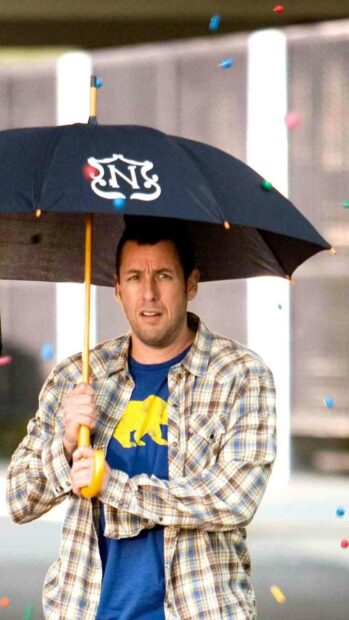 Adam Sandler is standing under a black umbrella with a yellow handle surrounded by colorful confetti, HD Mobile Wallpaper