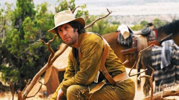 Adam Sandler is dressed in a cowboy outfit sitting outdoors near a campfire with horses nearby, HD Desktop Wallpaper
