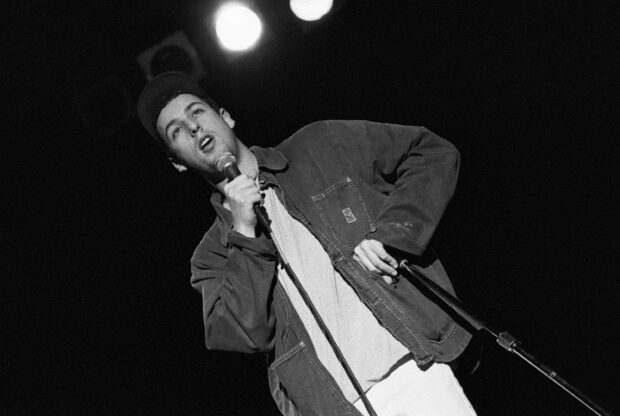 Adam Sandler is holding a microphone and speaking during a live performance, 2K Desktop Wallpaper
