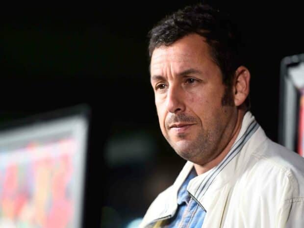 Adam Sandler looks thoughtful in a jacket with a blurred colorful background, 2K Desktop Wallpaper