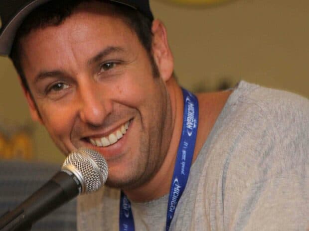 Adam Sandler smiling while speaking into a microphone during an event, 2K Desktop Wallpaper