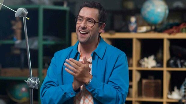 Adam Sandler is smiling and clapping his hands while wearing glasses and a blue jacket in a cozy room, HD Desktop Wallpaper