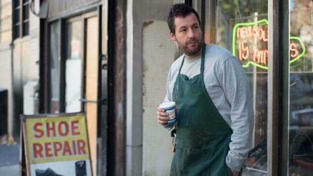 Adam Sandler wearing a green apron and holding a coffee cup outside a shoe repair shop, 4K Desktop Wallpaper