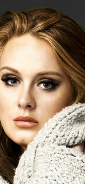 Adele wallpapers showing a close up of a woman with striking eyes and soft curls wrapped in a textured knit, 2K Mobile Wallpaper