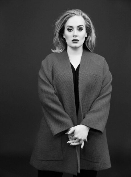 Adele Wallpapers features a confident woman standing with hands clasped against a dark background, 2K Phone Wallpaper