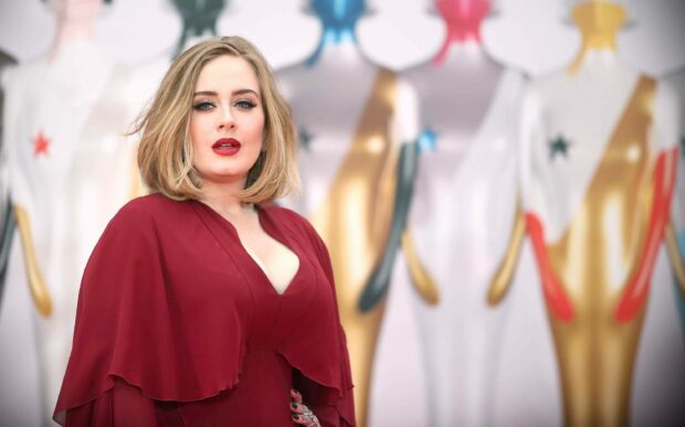 Adele looks confident wearing a red dress with a soft background of golden statues, 2K Desktop Wallpaper