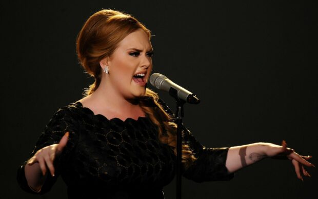 Adele is singing passionately into a microphone during a live performance, 2K Desktop Wallpaper