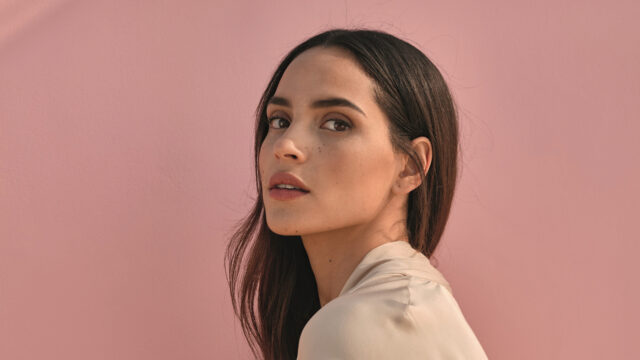 Adria Arjona close up portrait with natural makeup and soft pink background wallpaper