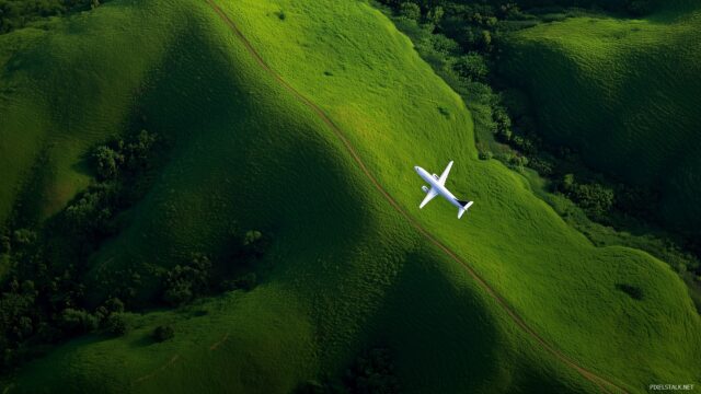 Airplane Desktop Background Free Download, An Airplane Flying Low Over A Vibrant Green Landscape, Showcasing Nature Beauty