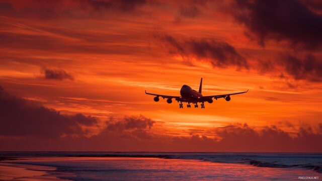 Airplane HD Background For Mac, An Airplane Silhouetted Against A Fiery Sunset Over The Ocean, Creating A Stunning Contrast