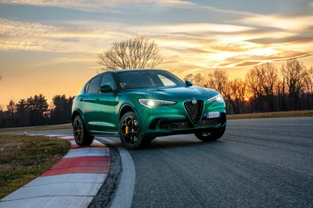 A green Alfa Romeo is parked on a racetrack during sunset with trees in the background, 2K Desktop Wallpaper