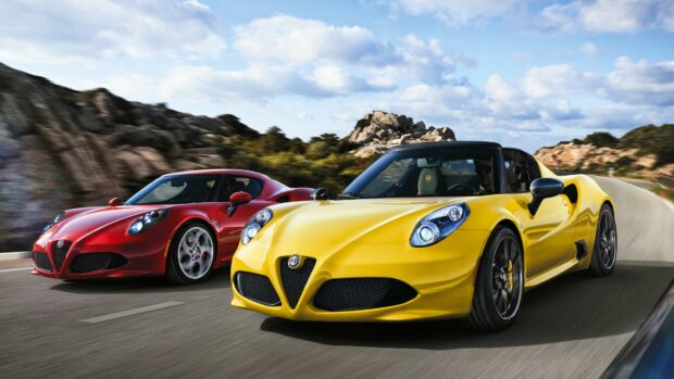 Two Alfa Romeo sports cars in yellow and red drive on a curvy road with rocky hills in the background, 4K Desktop Wallpaper