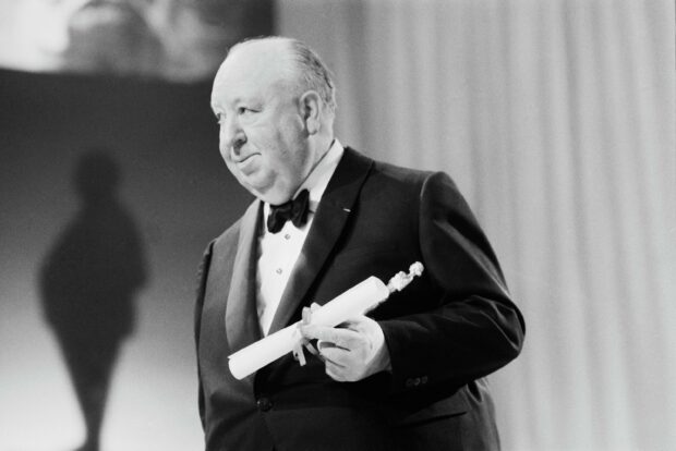 Alfred Hitchcock is seen holding an award while wearing a tuxedo at a formal event, 2K Desktop Wallpaper