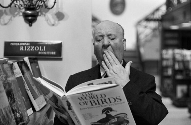 Alfred Hitchcock is yawning while reading a book titled The World of Birds in a bookstore, HD Desktop Wallpaper