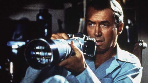 A man aiming a camera lens intently in a suspenseful moment inspired by Alfred Hitchcock, 4K Desktop Wallpaper