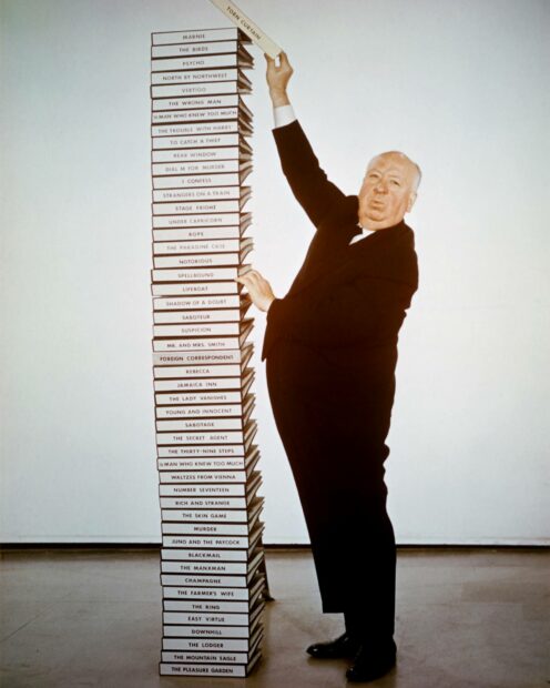 Alfred Hitchcock is standing next to a tall stack of his movie scripts, Alfred Hitchcock Wallpapers, HD Desktop Wallpaper
