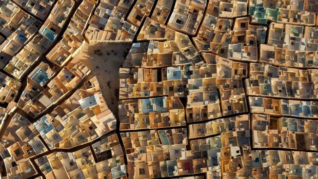 A detailed aerial view shows the packed buildings and narrow streets of an ancient city in Algeria, HD Desktop Wallpaper
