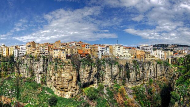 A panoramic view of an ancient city built on cliffs under a partly cloudy sky in Algeria, HD Desktop Wallpaper