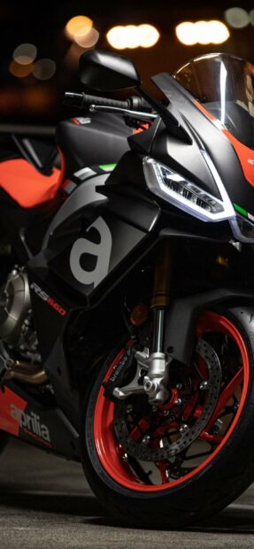 The Aprilia RS 660 sport bike is shown close up focusing on the front wheel and headlight details, 2K Phone Wallpaper