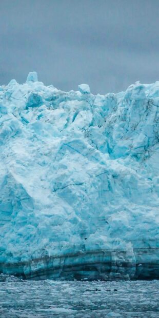 A massive blue glacier ice formation rising above the cold ocean in the Arctic region, HD Mobile Wallpaper
