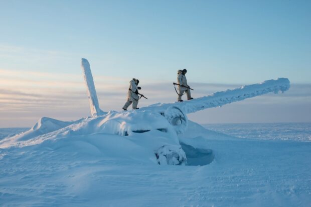 Two soldiers in winter gear walk on a snow covered plane wreck in the arctic, 2K Desktop Wallpaper
