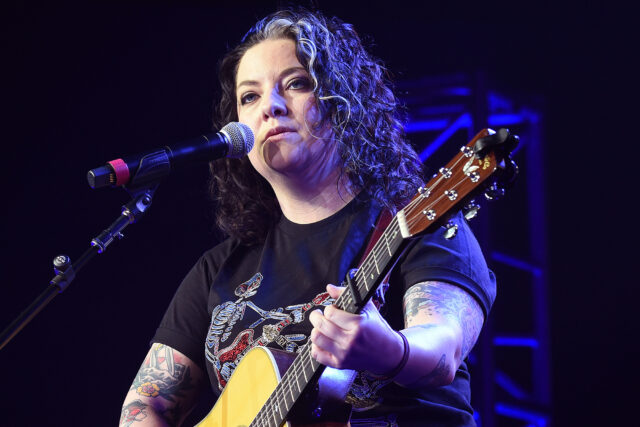 Ashley McBryde Performing With Guitar On Stage Wallpaper