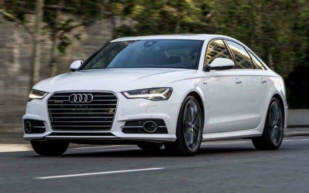 A white Audi A6 driving on a city street with modern buildings in the background, HD Desktop Wallpaper