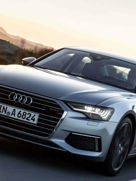 The Audi A6 is driving on a road with its headlights on during sunset, HD Desktop Wallpaper