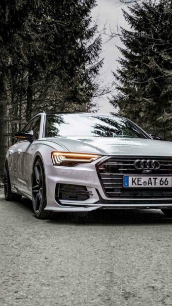 A white Audi A6 is parked on a forest road with trees reflected on its windshield, HD Phone Wallpaper