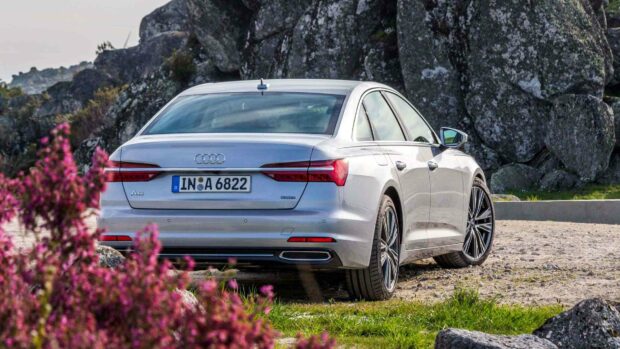 The silver Audi A6 is parked on a dirt path surrounded by rocks and blooming flowers, HD Desktop Wallpaper