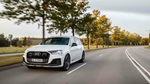 A white Audi Q7 is driving smoothly on a curved road surrounded by green trees under a cloudy sky, 4K Desktop Wallpaper
